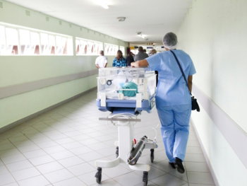person walking on hallway in blue scrub suit near incubator